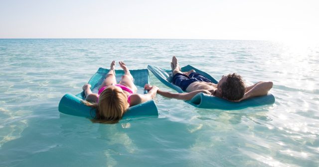 Two adults floating in the sea on a mat